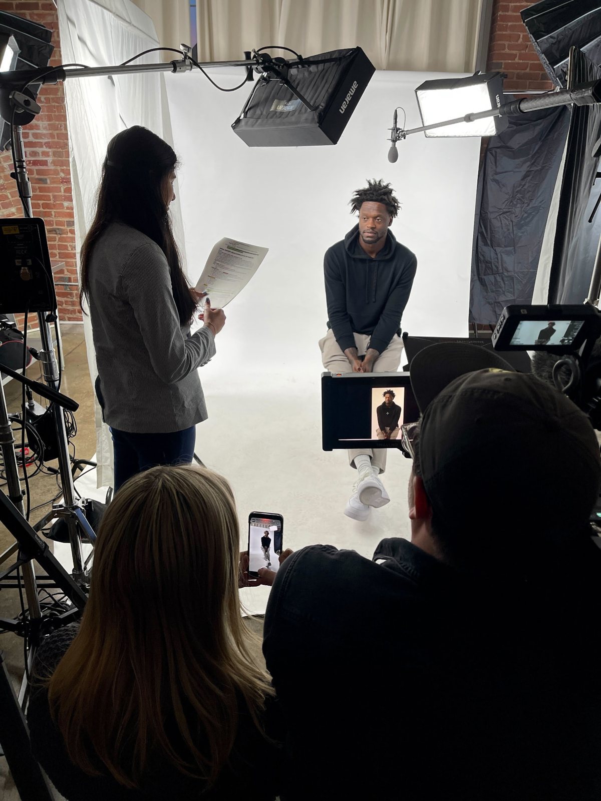 Reilly reviewing interview notes on a lit studio set with Julius Randle