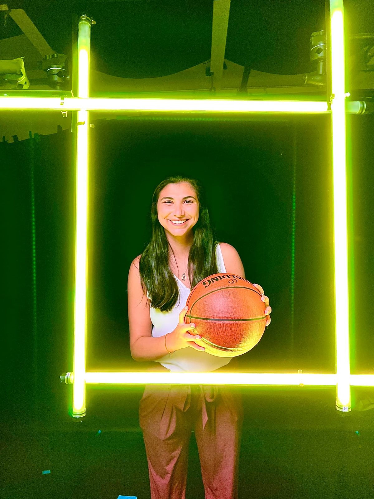 Reilly holding a basketball inside a neon light frame on set