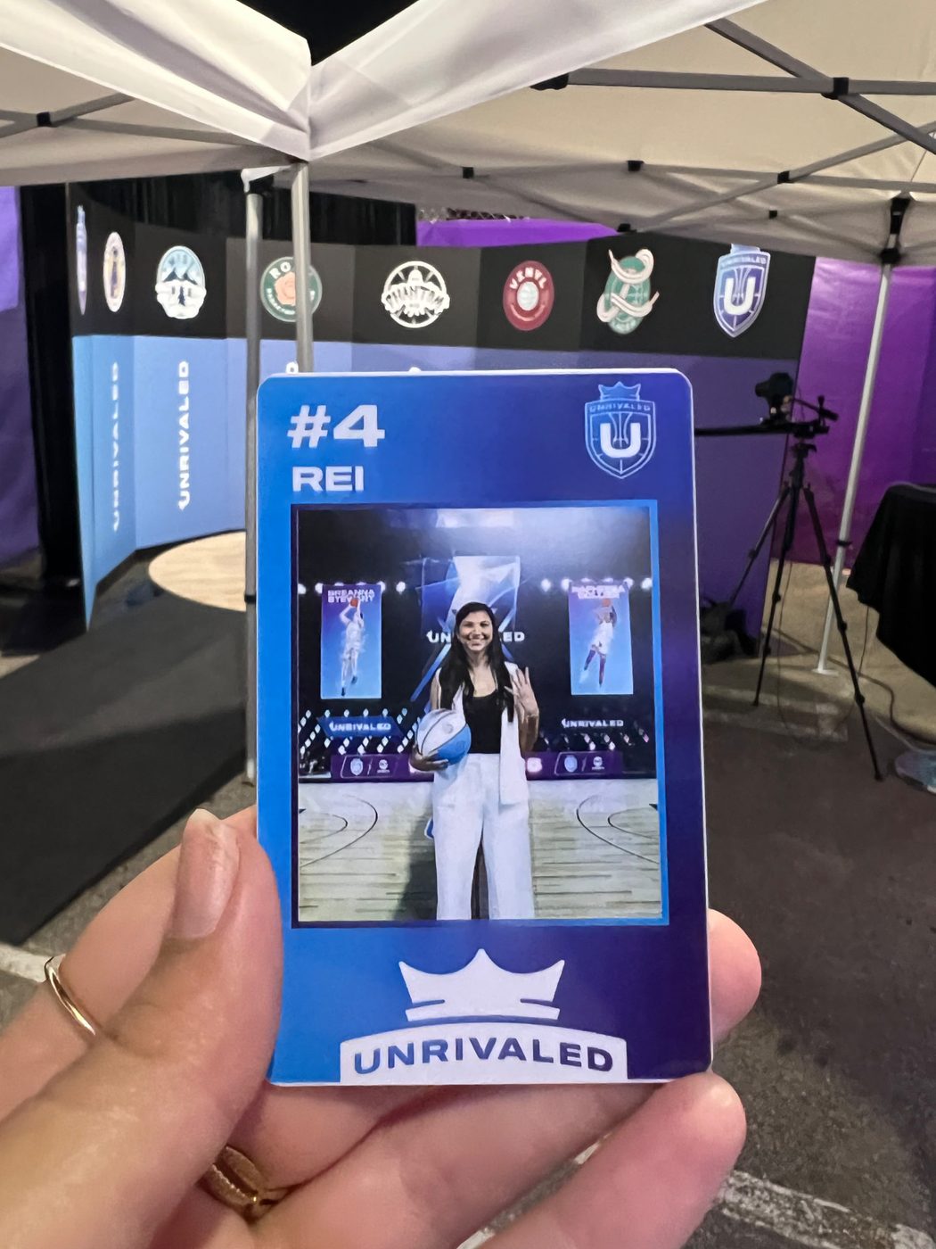 Unrivaled event credential for Reilly held up in front of the league's team logos on site